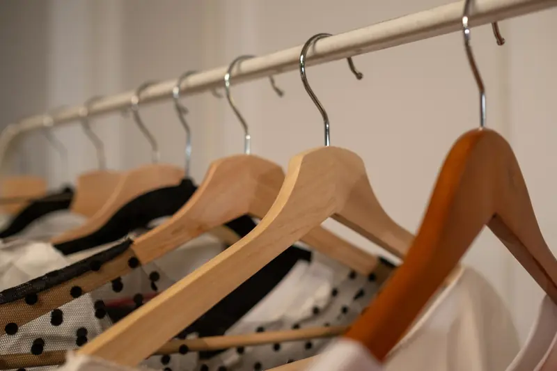 Close-up of wooden clothes hangers with assorted clothing indoors