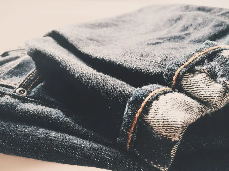 Detailed view of folded denim jeans in soft, warm lighting