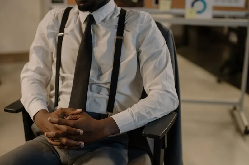 Close-up of a business professional in a chair, wearing a tie and suspenders, in an office setting