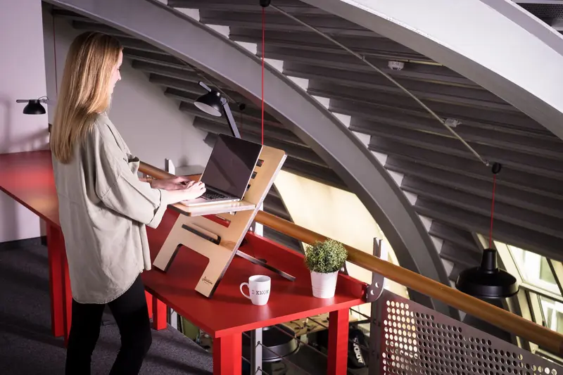 Woman using a laptop on a standing desk indoors in a creative workspace
