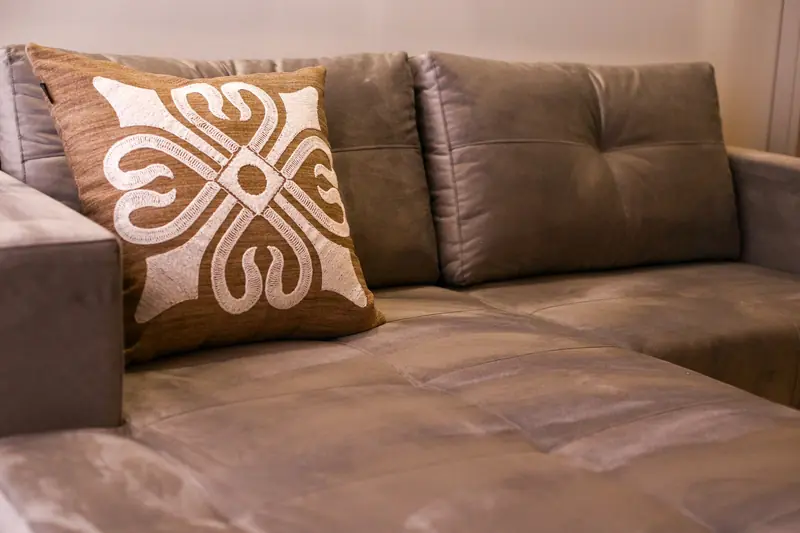 A close-up of an elegant gray sofa with an artistic decorative cushion in a modern living room