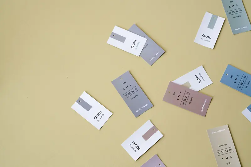 Floating clothing tags in various colors against a yellow backdrop with ample copy space