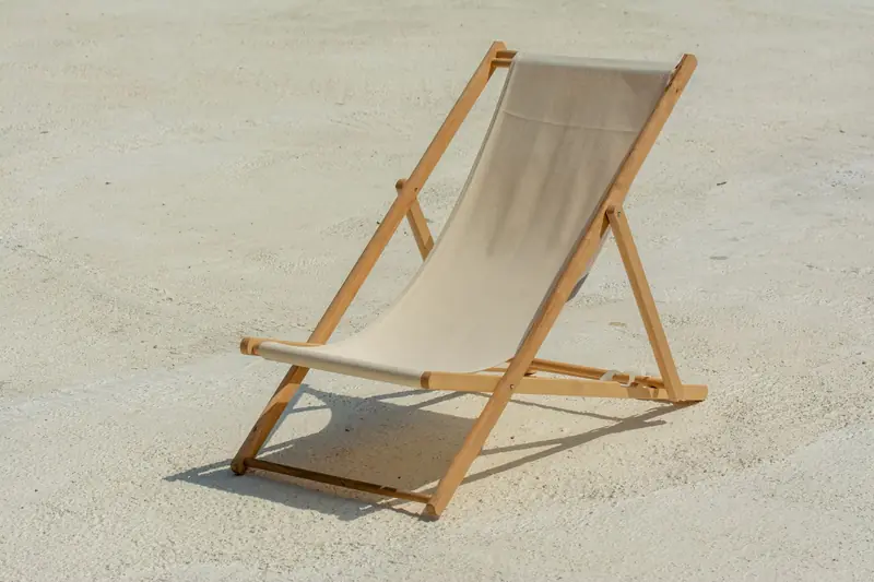 Minimalist outdoor scene featuring an empty sunlit deck chair on the beach, perfect for vacation themes