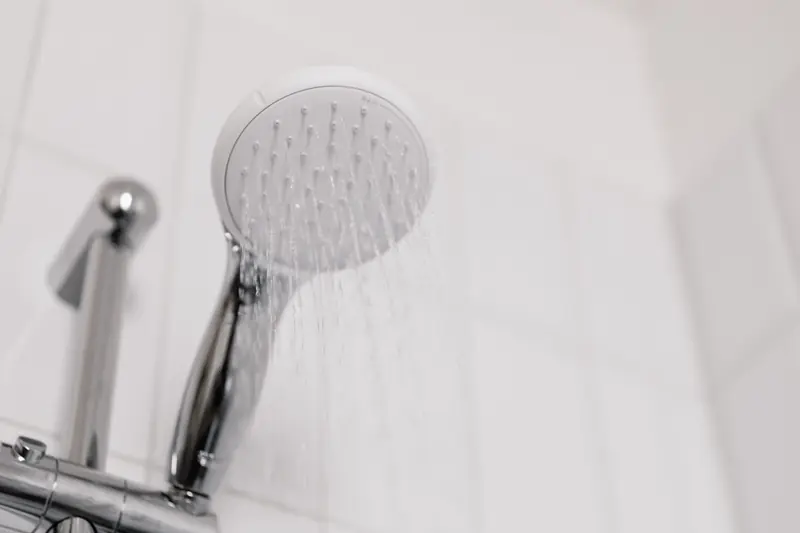 Stylish clean shower head with water flow in a white tiled bathroom
