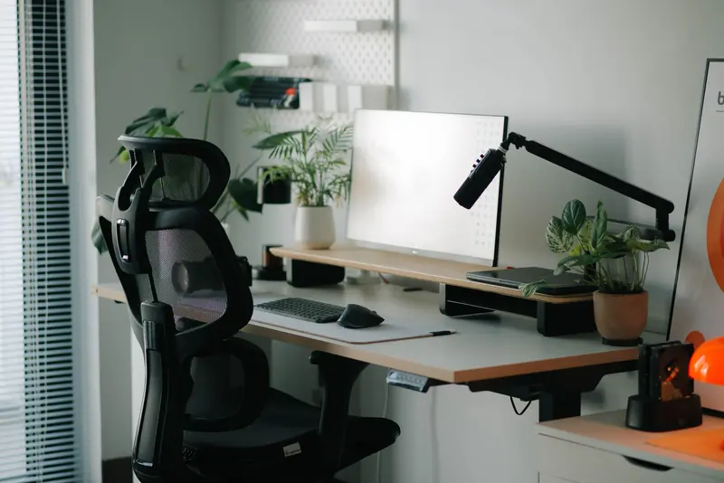Stylish home office setup with ergonomic chair, plants, and modern desk accessories