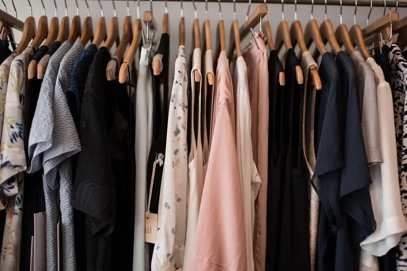 A stylish collection of women's clothing hanging on wooden hangers in a boutique setting